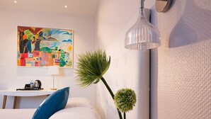 A modern hotel room with a bed, a desk, a lamp, a wall-mounted painting, and a potted plant. - Hôtel Escale Oceania Lorient (Lorient)