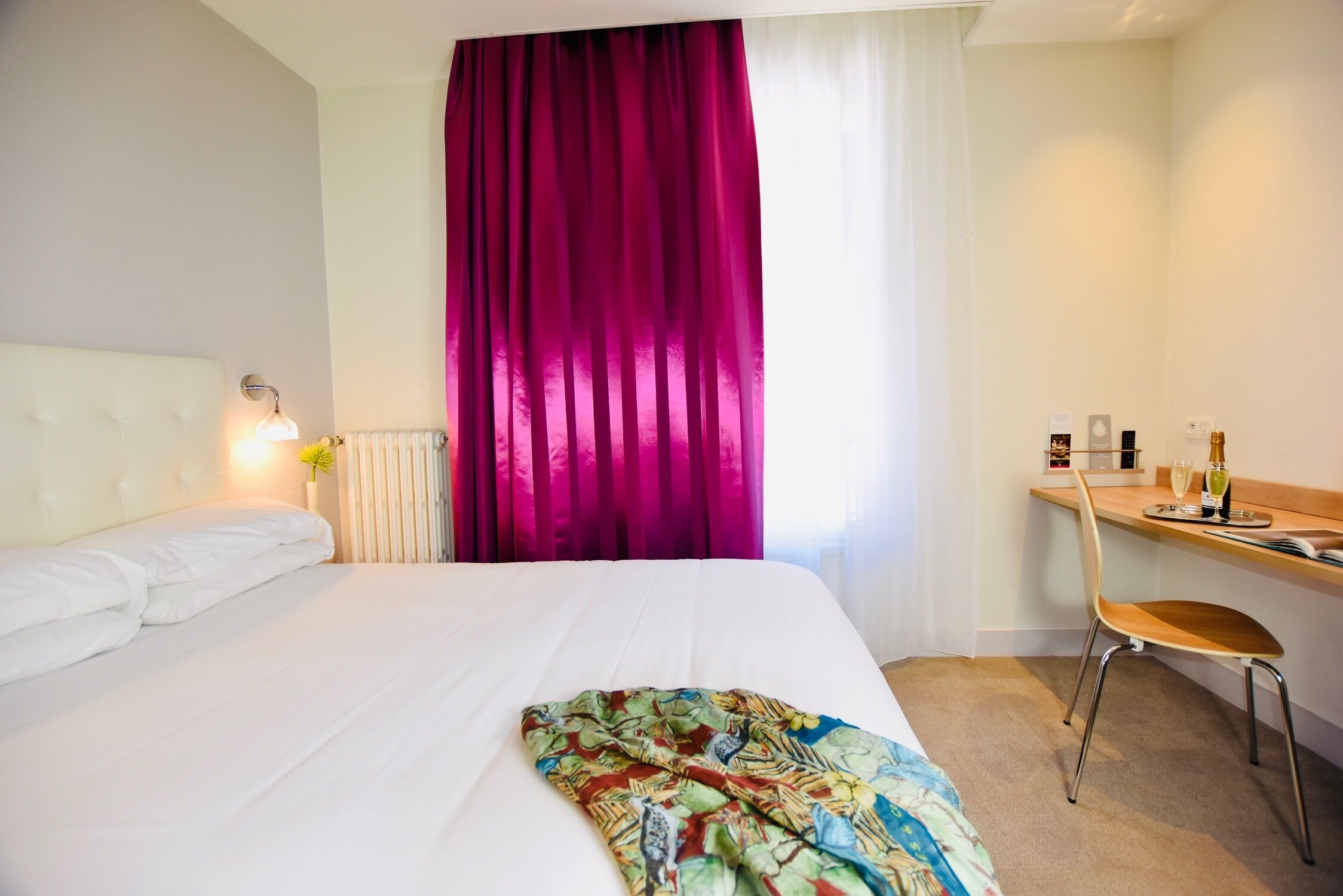 A hotel room with a bed, a desk, and a chair.