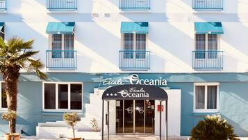 A hotel named 'Escale Oceania' with a modern facade, blue balconies, and a clear entrance.