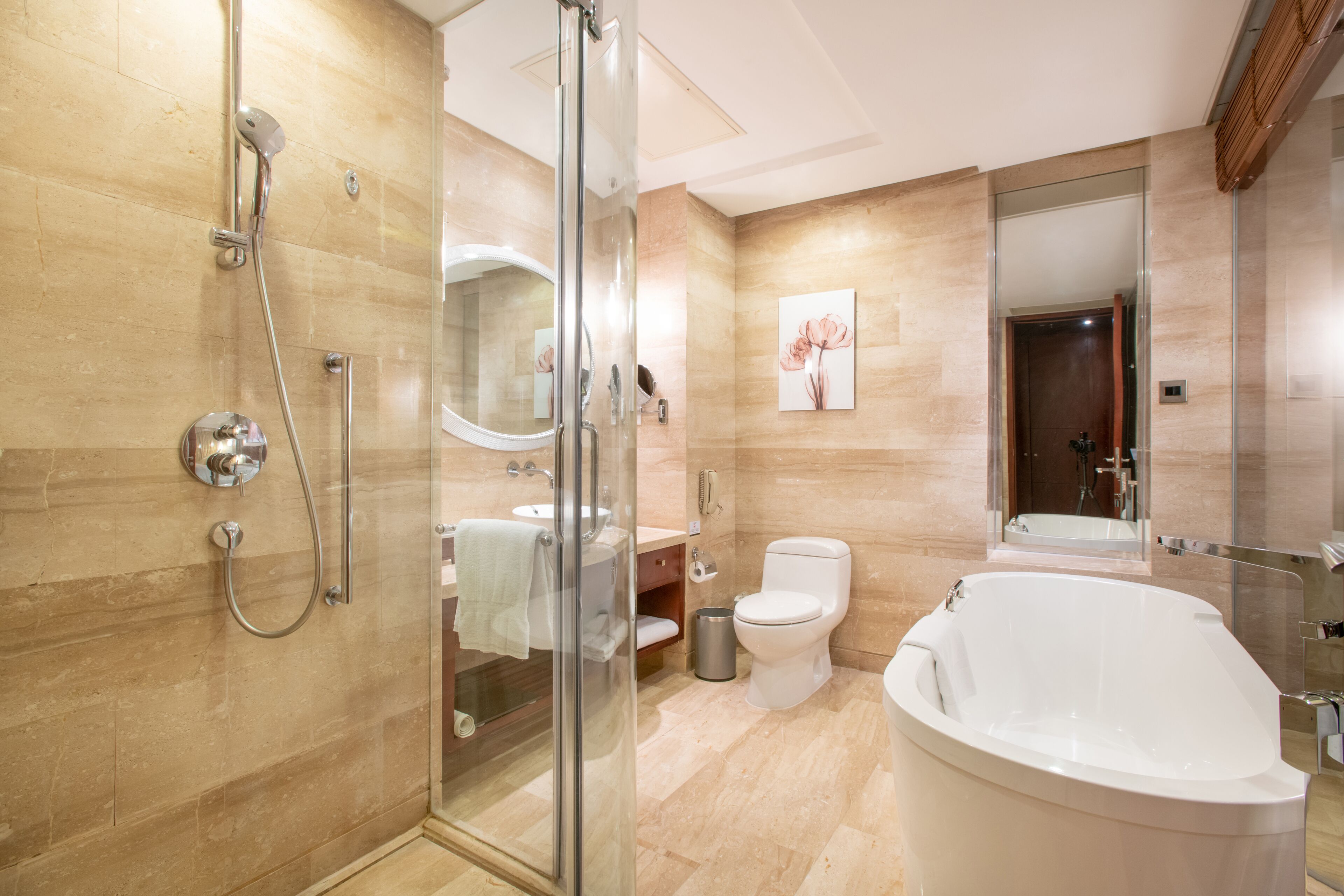 Un baño moderno con ducha envuelta en vidrio, una bañera independiente y un inodoro.