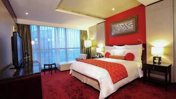 A hotel room with a large bed, a desk, a chair, a TV, and a window with curtains.