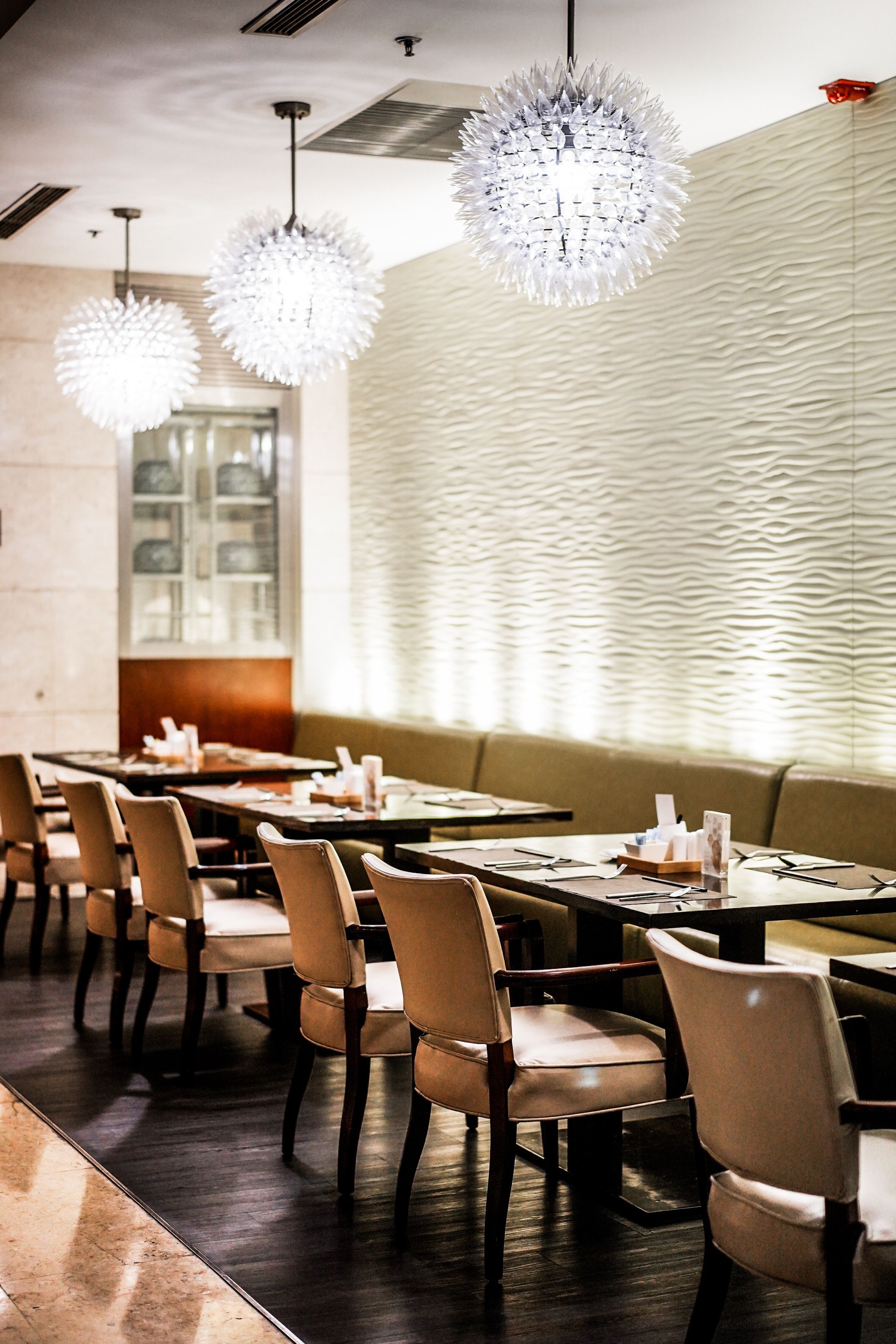 A restaurant with long tables, chairs, and decorative spherical light fixtures.