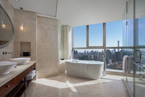 A modern bathroom with two sinks, a freestanding bathtub, and a large window offering a city view.
