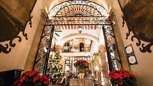 An ornate wrought iron gate with a fan-like design, leading to a grand interior with classical architecture and a Christmas tree. - Casa Pedro Loza (Guadalajara)