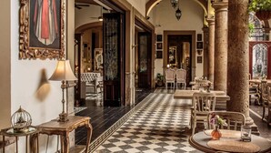 A hotel lobby with a checkered floor, classic furniture, and a large framed painting. - Casa Pedro Loza (Guadalajara)