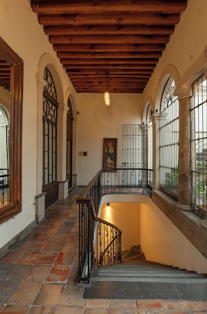 A staircase with a wooden handrail and black metal balusters, leading to a lower level. - Casa Pedro Loza (Guadalajara)