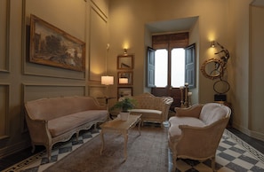 A classic interior with a checkered floor, a large framed painting, and a window with shutters. - Casa Pedro Loza (Guadalajara)