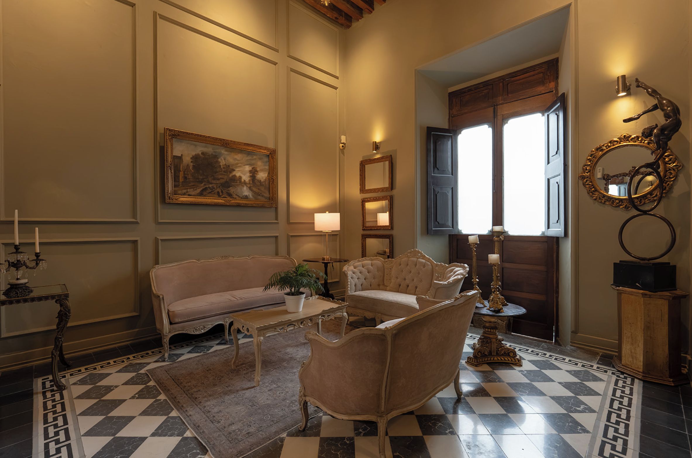 A room with a checkered floor, a sofa, a chair, a table with a plant, and a painting on the wall.
