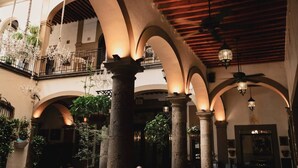 An interior courtyard with arches, columns, and hanging chandeliers. - Casa Pedro Loza (Guadalajara)