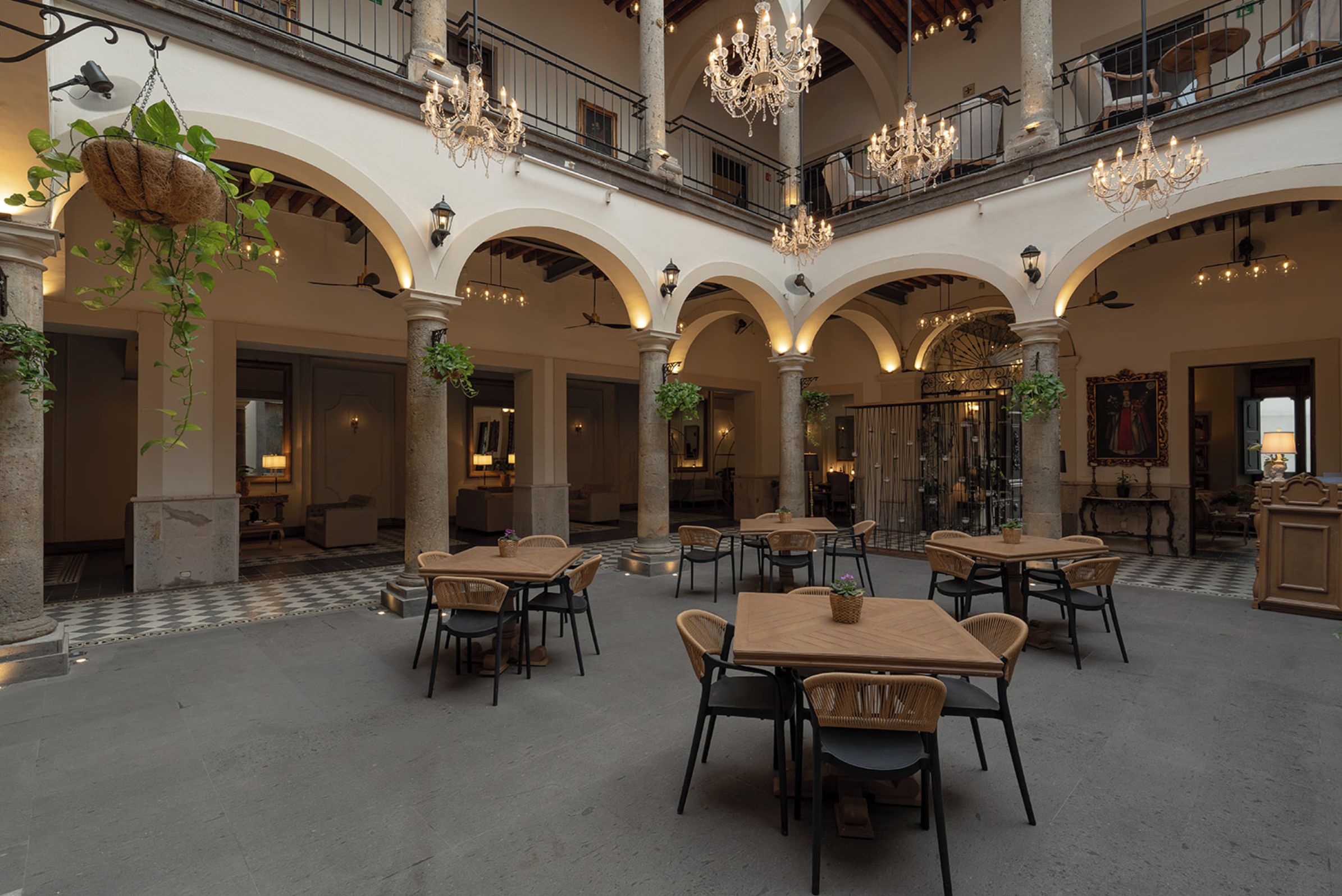 Un amplio patio interior con varias zonas de estar, candelabros e instalaciones de plantas colgantes.