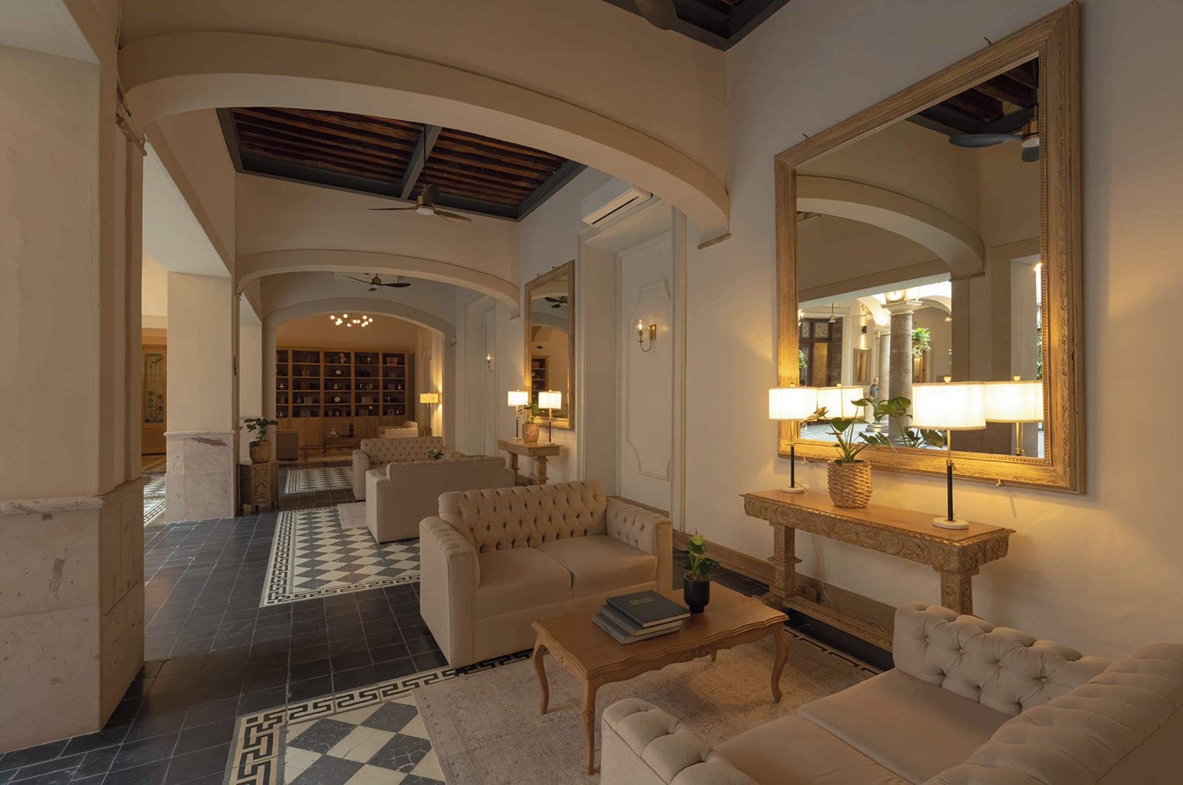 A spacious lobby with a checkered floor, a large mirror, and a seating area with sofas and a coffee table.