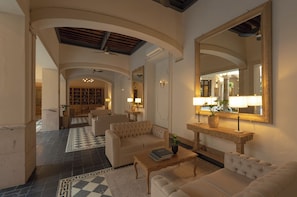 A spacious lobby with a checkered floor, a large mirror, and a seating area with sofas and a coffee table.