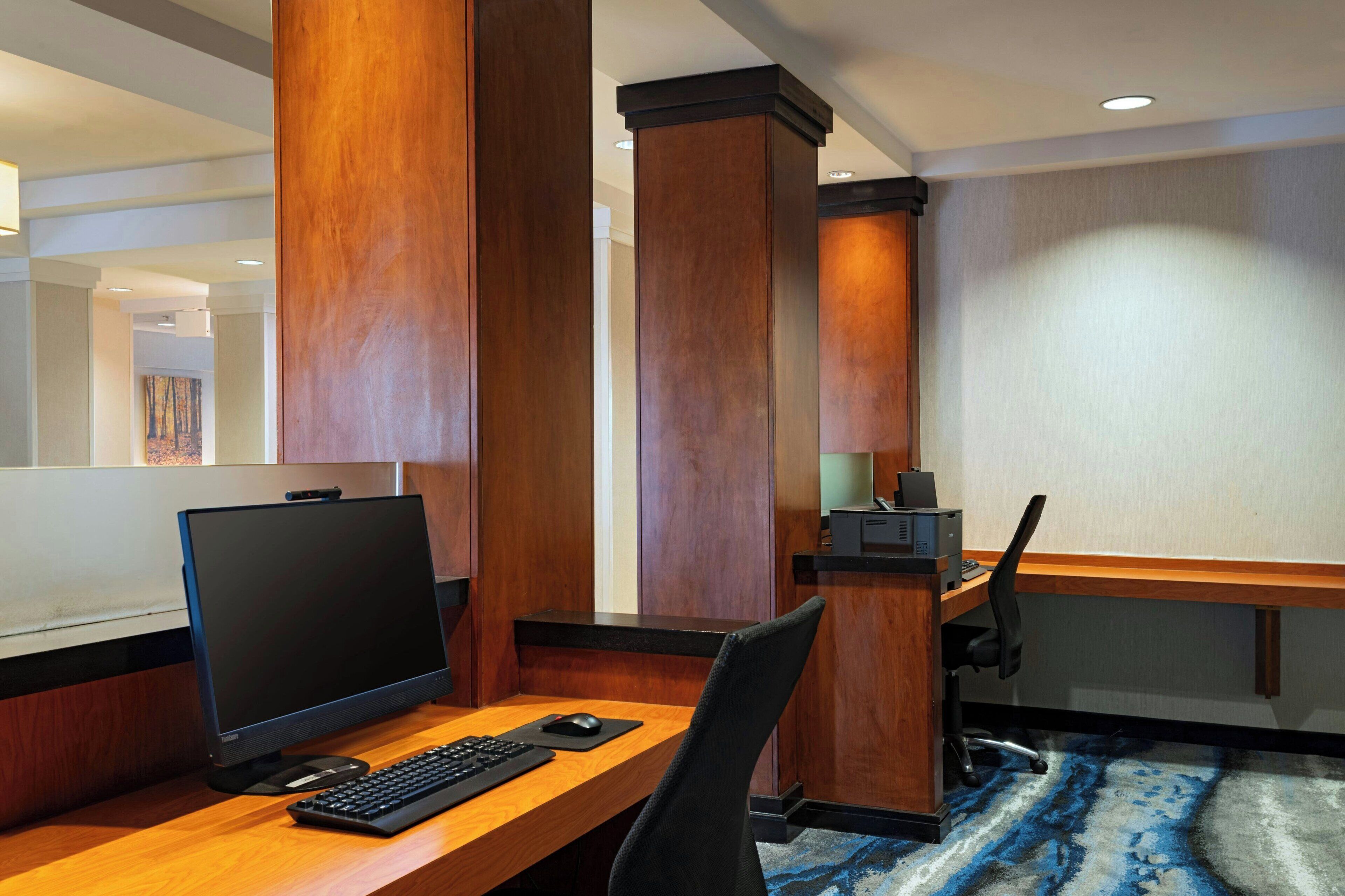 A hotel room with a wooden desk, a computer, and a chair.