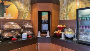 A breakfast bar with a refrigerated display, a fruit bowl, and a beverage dispenser. - Fairfield Inn & Suites by Marriott San Antonio NE/ Schertz (Schertz)