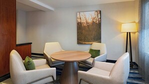 A hotel room with a round table, two armchairs, a lamp, and a painting on the wall. - Fairfield Inn & Suites by Marriott San Antonio NE/ Schertz (Schertz)