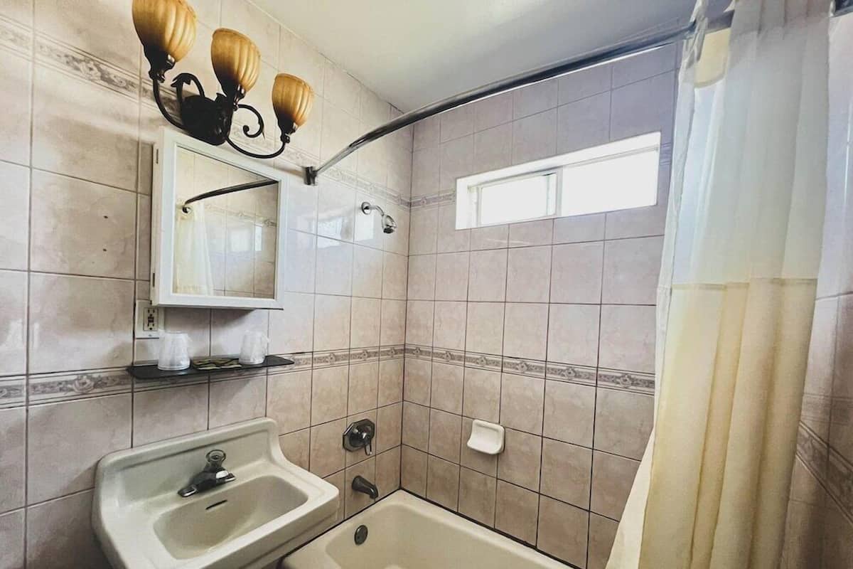 A bathroom with a sink, mirror, shower, and a towel rack.