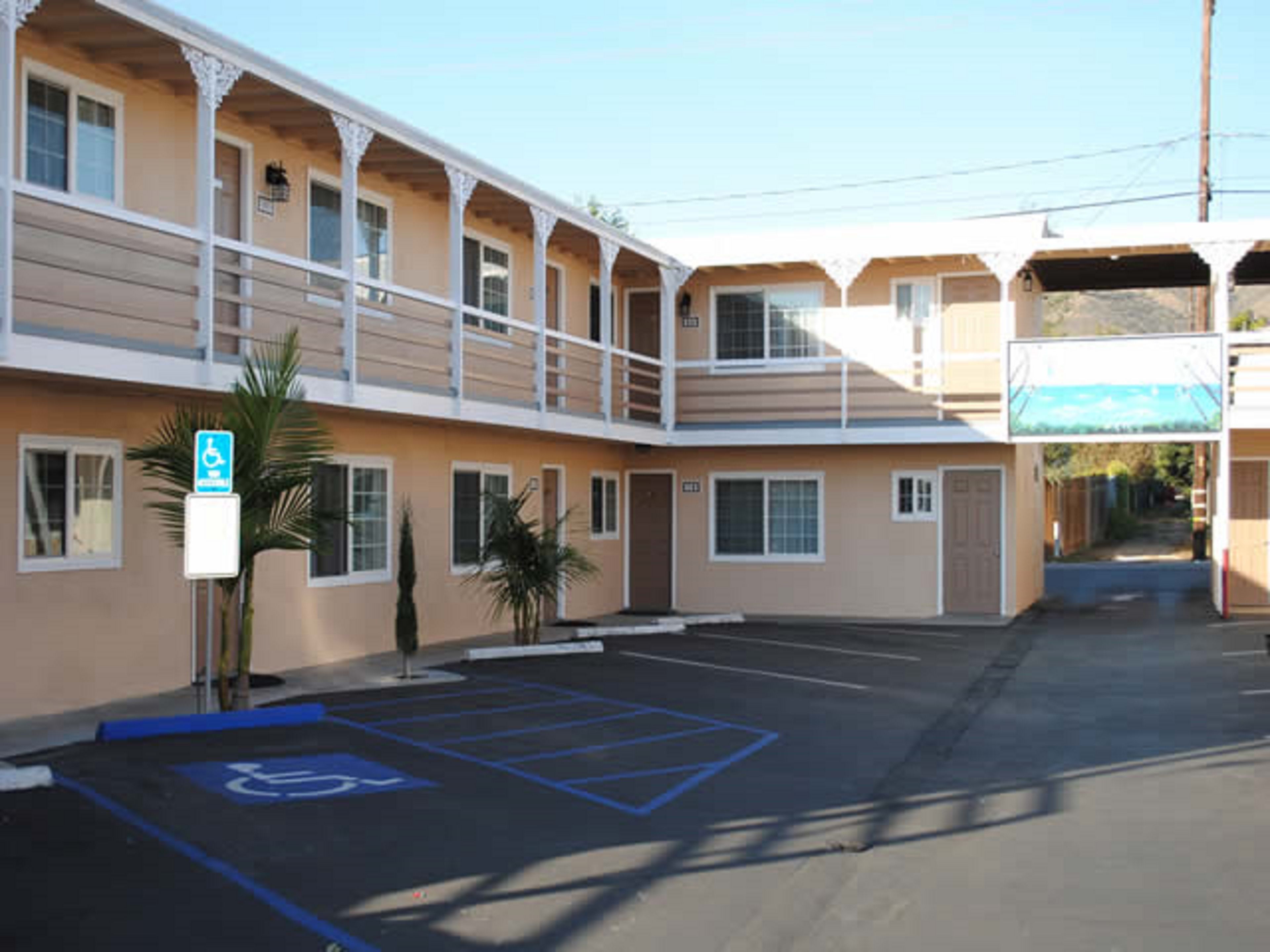Un motel con estacionamiento, espacios de estacionamiento para discapacitados y un letrero que indica una entrada accesible para discapacitados.