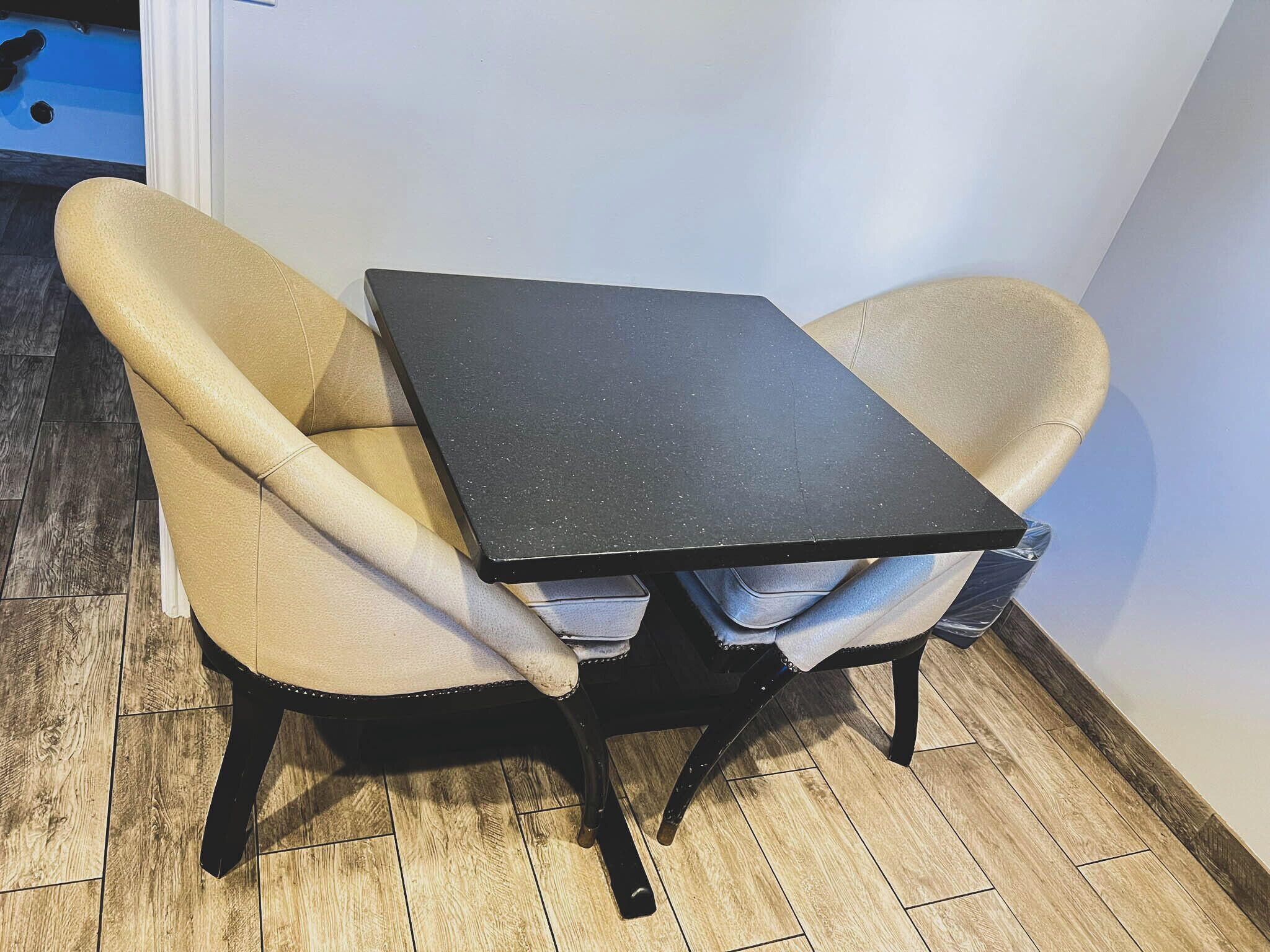 A small, dark-colored table with two beige chairs.