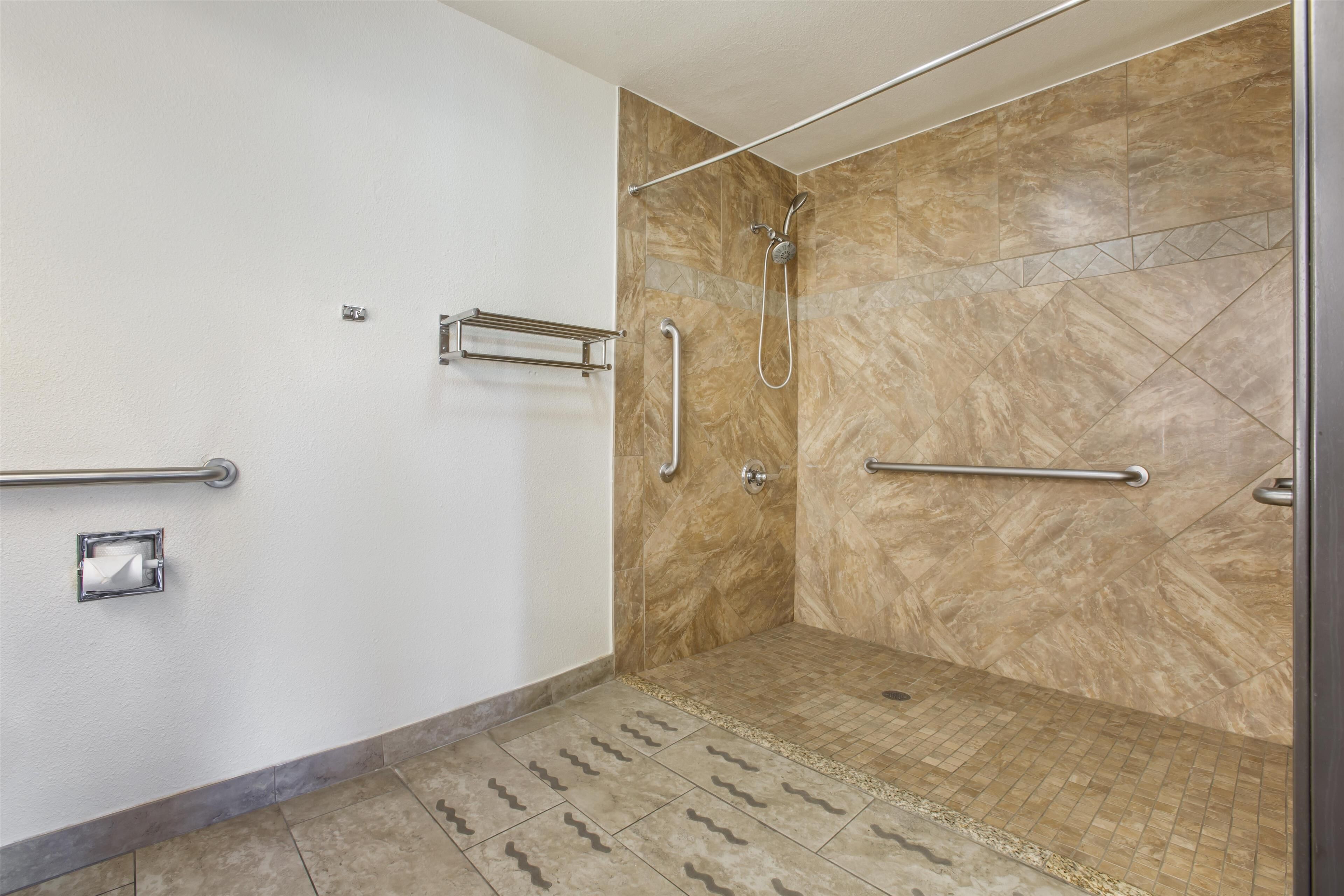 Ein Badezimmer mit Dusche, Haltegriffen und einer Handstange.