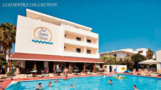 Un hôtel doté d’une piscine, d’un espace extérieur couvert et d’un bâtiment sur lequel est apposée une enseigne indiquant « Hôtel Cléopâtre Classic ».