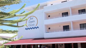 Un hôtel appelé « Hôtel Cléopâtre Classic », avec un toit rouge et de nombreux balcons.