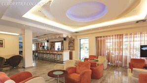 Un hall d’hôtel comprenant des espaces de détente, un bar et un téléviseur.