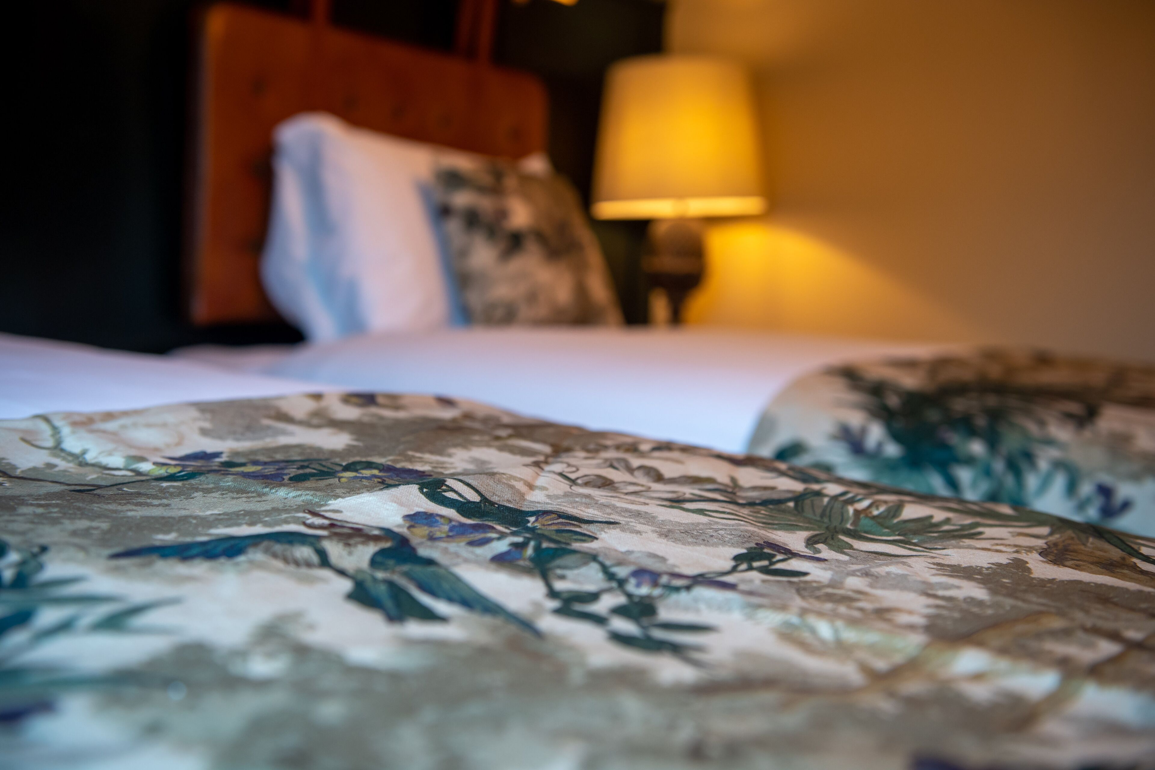 A bed with floral-patterned bedding and a wooden headboard.