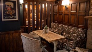 A wooden table with a vase and a candle, a floral sofa, and a poster on the wall. - Red Lion Todwick by Chef and Brewer Collection (Sheffield)