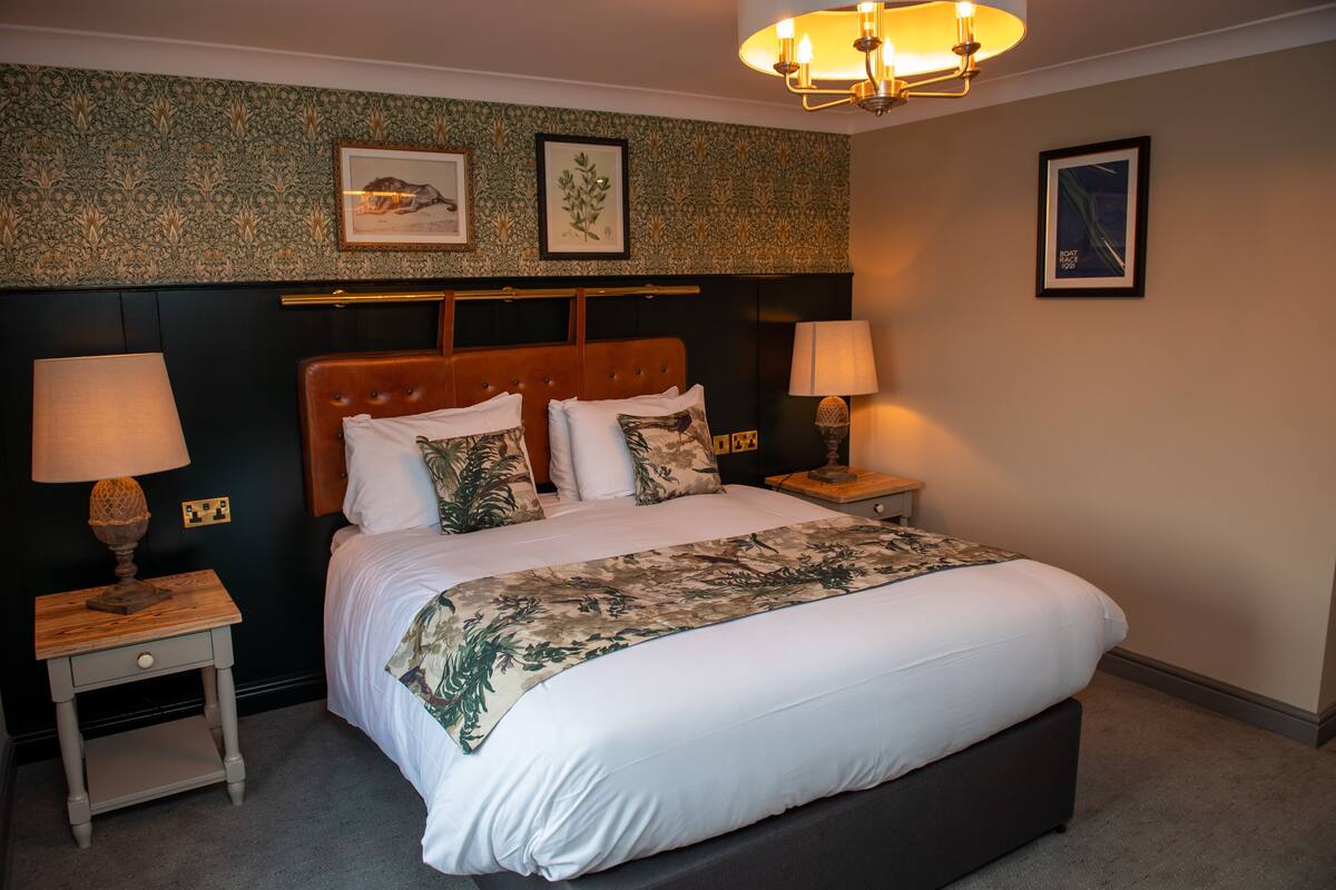 A neatly made bed with a floral bedspread, two bedside lamps, and framed artwork on the wall.