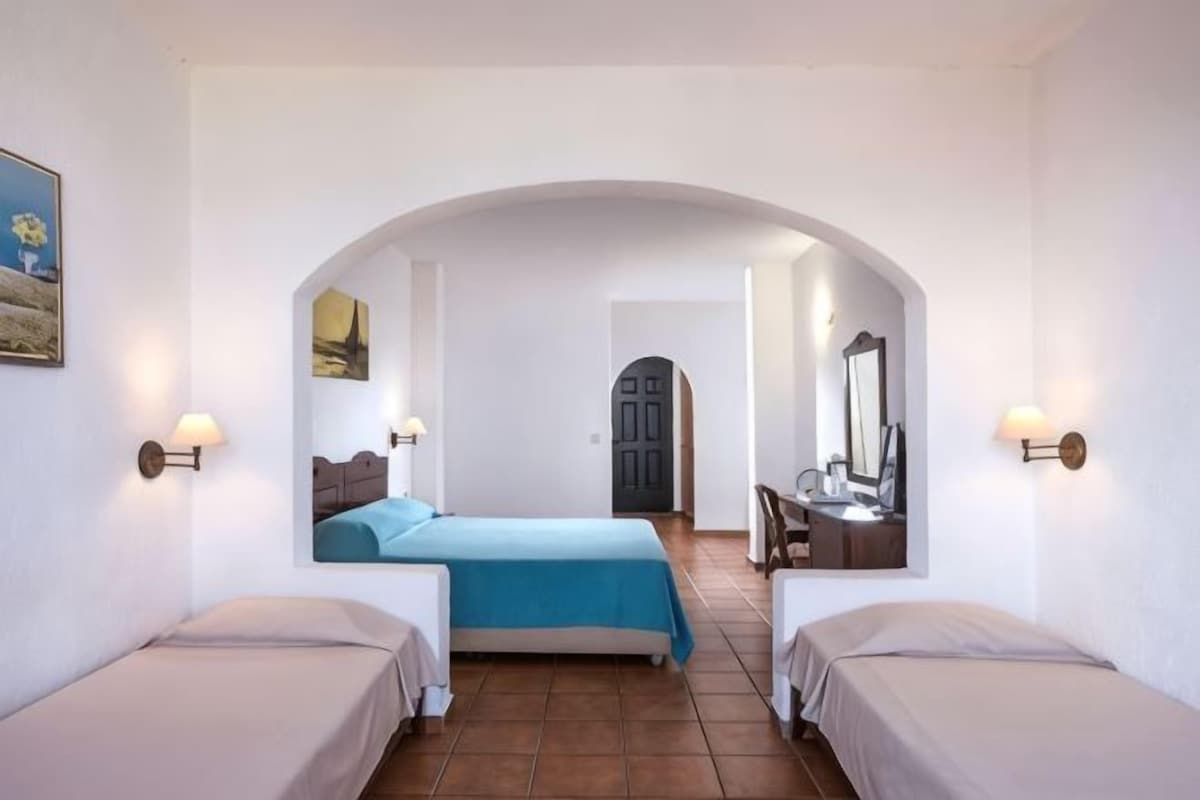 Quarto com duas camas, uma escrivaninha, uma cadeira e um espelho.