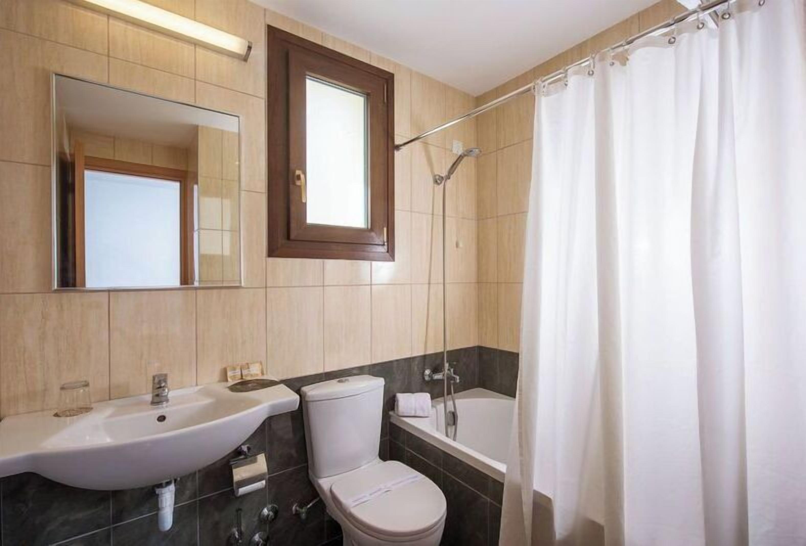 A bathroom with a sink, toilet, bathtub, and a shower curtain.