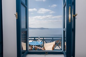 Ein Balkon mit Tisch und Stühlen mit Blick auf ein Gewässer und entferntes Land.