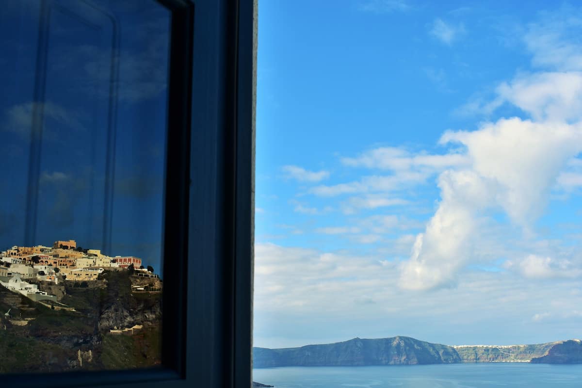 A coastal town with buildings on a cliff, a clear sky, and calm sea.