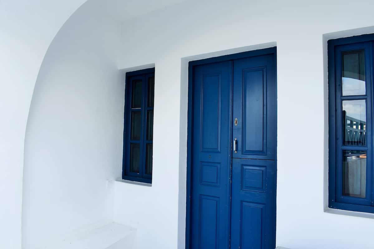 A white building with a large blue door and two windows.