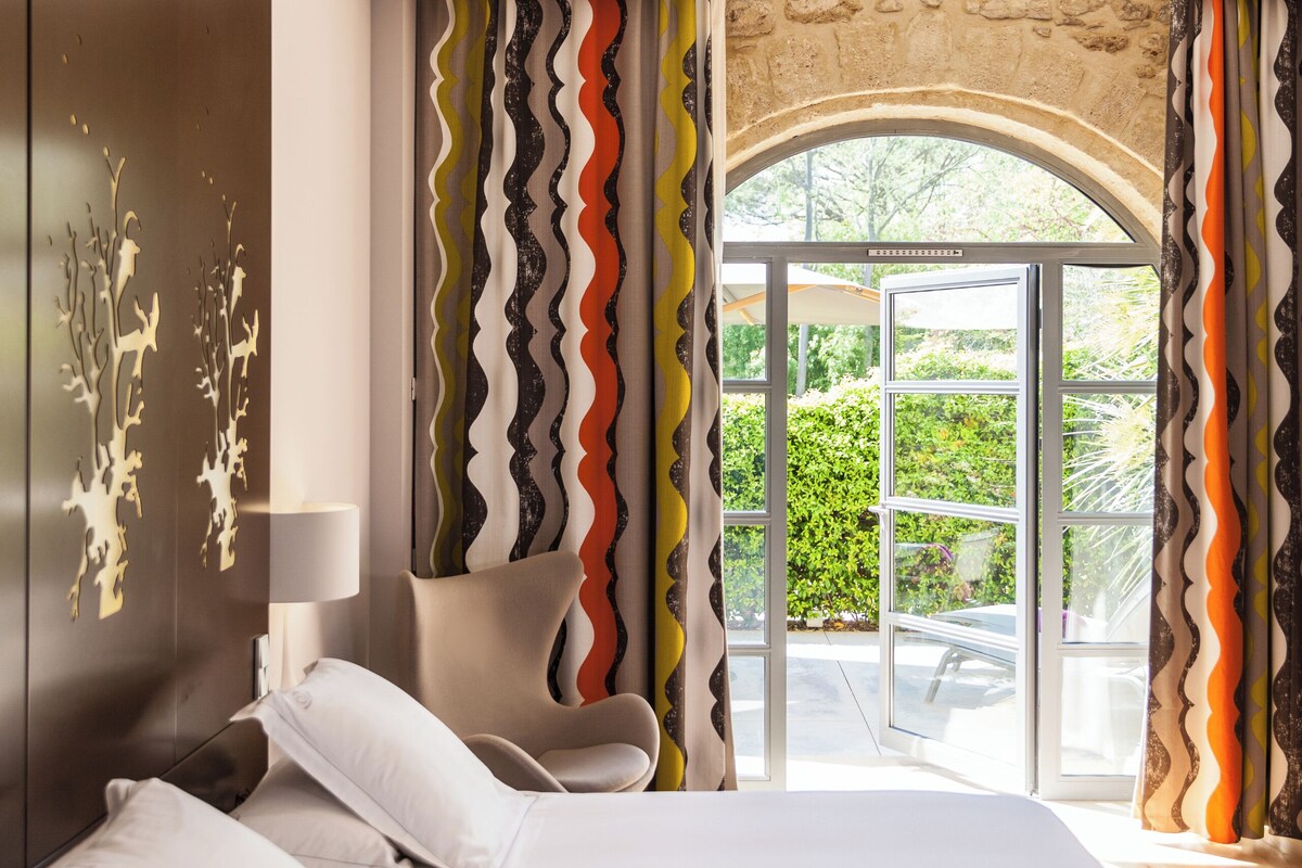 Un dormitorio moderno con una cama, una silla y vistas a través de una puerta de cristal.