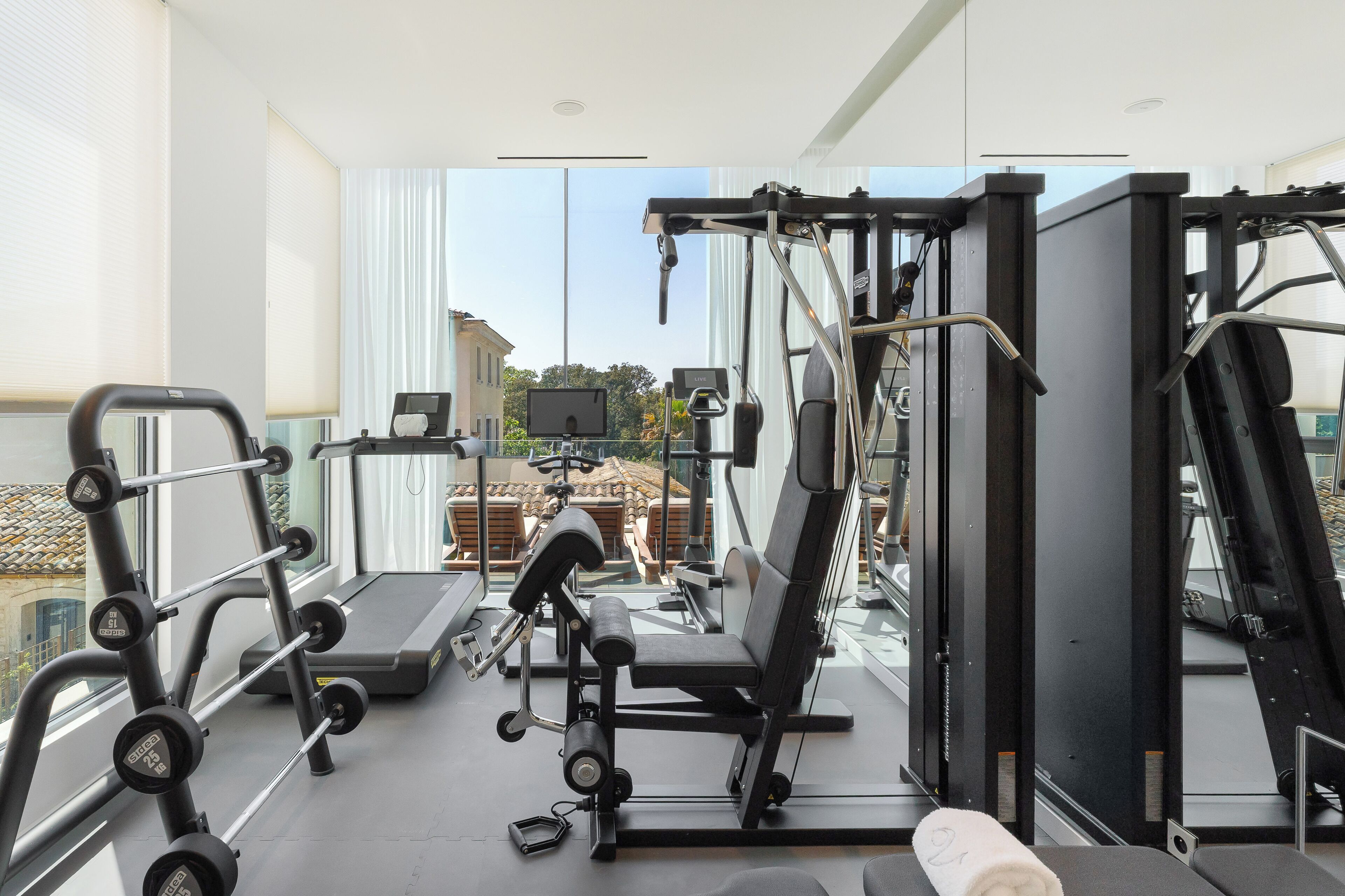 A gym with exercise equipment, a treadmill, and a view of buildings outside.