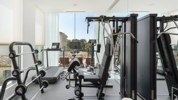 A gym with exercise equipment, a treadmill, and a view of buildings outside.