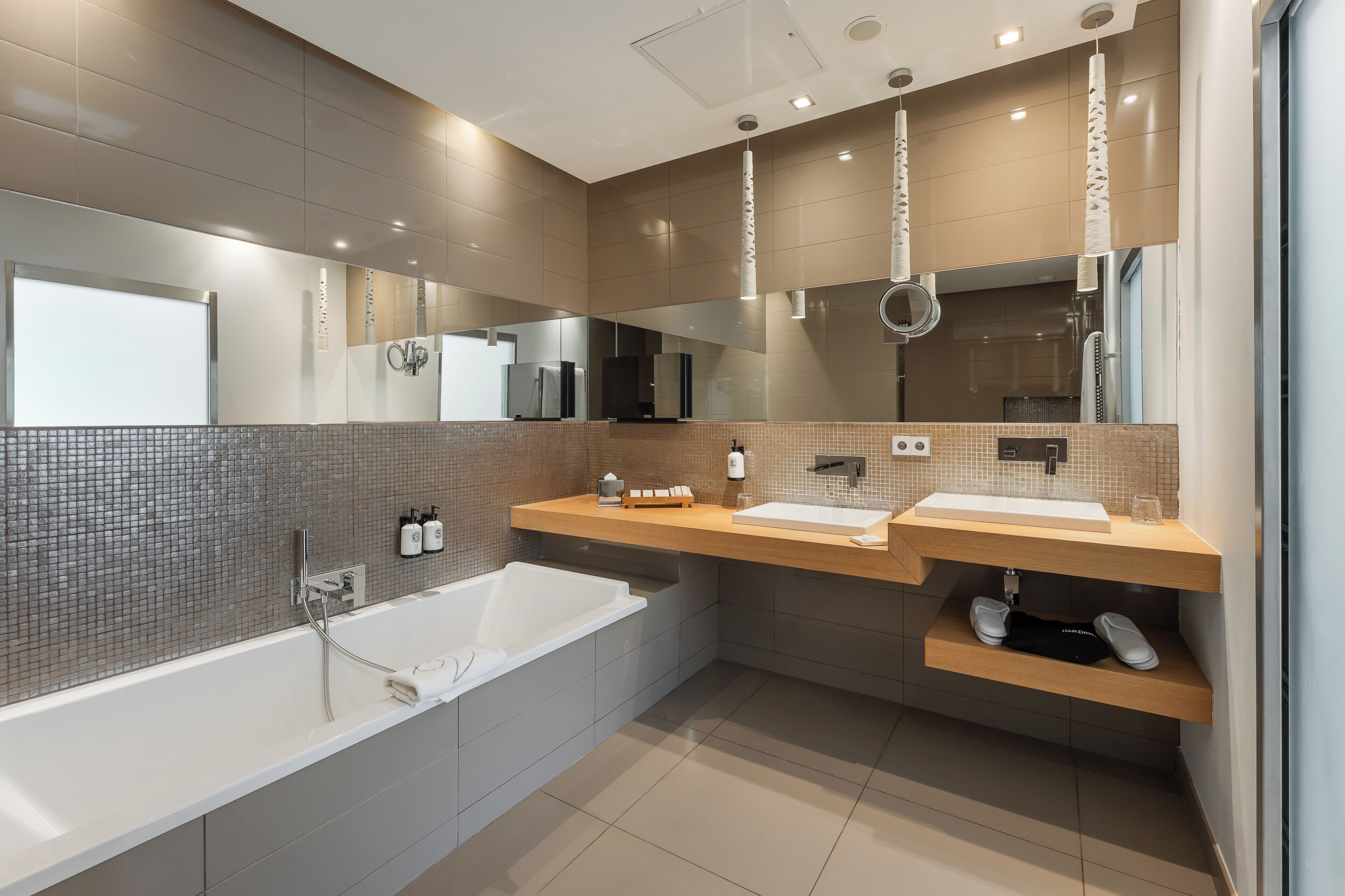 A modern bathroom with a large bathtub, two sinks, and a mirror.