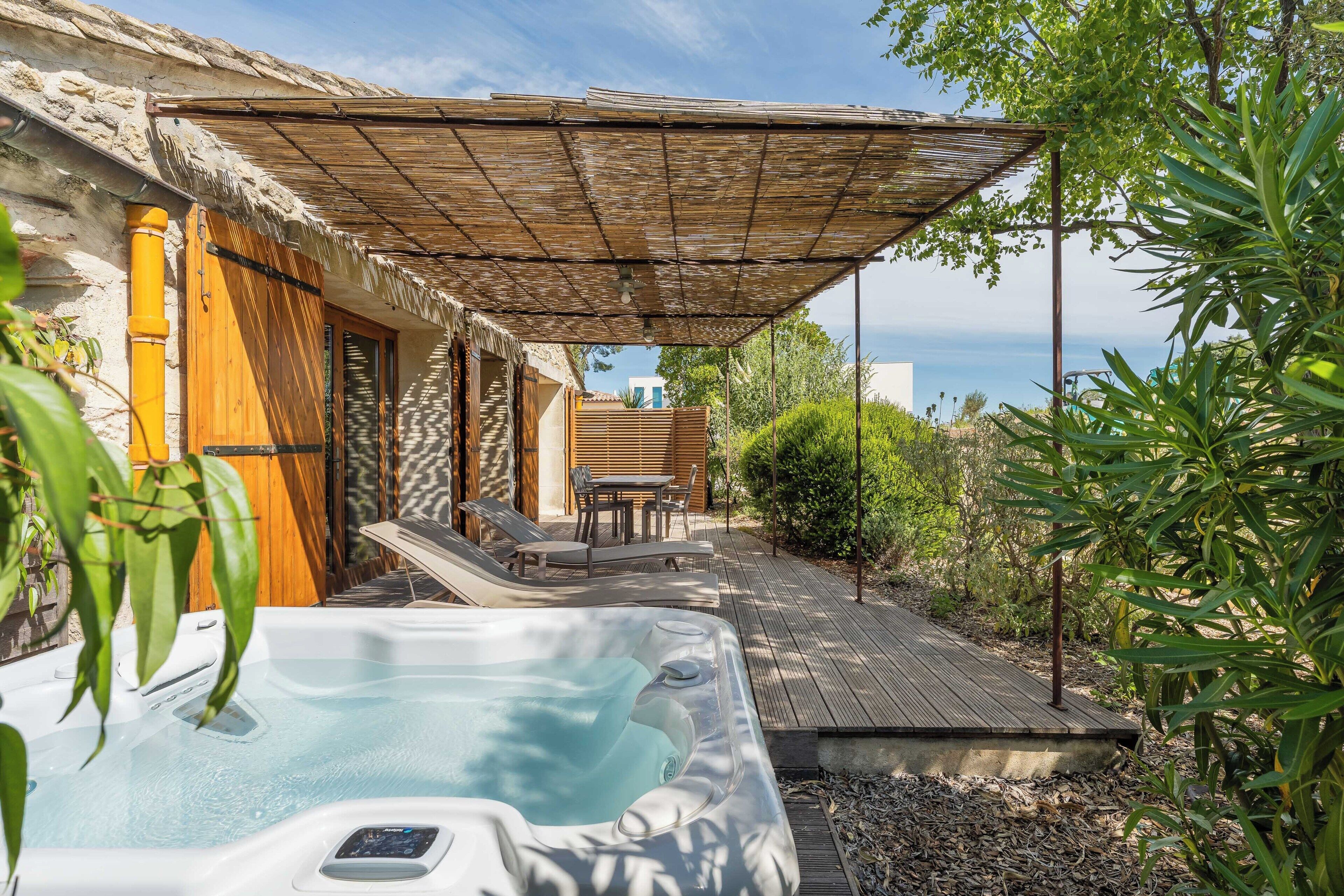 A hot tub, wooden deck, outdoor seating, and a view of the sea.