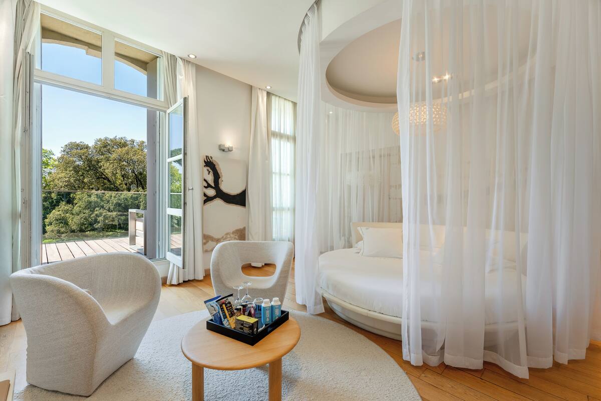 Een moderne hotelkamer met een groot raam, een bed, een stoel en een tafel met een dienblad.