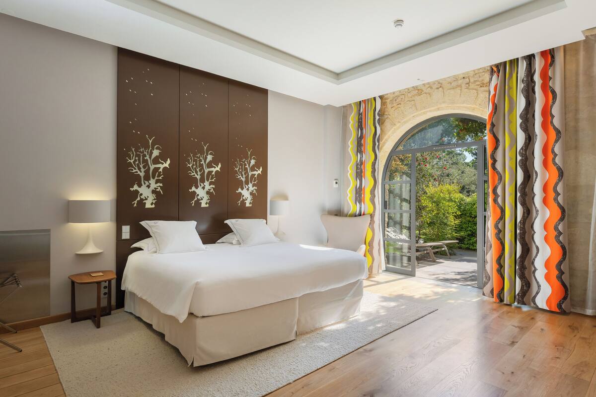 Een slaapkamer met een bed, nachtkastjes en uitzicht op een terras.