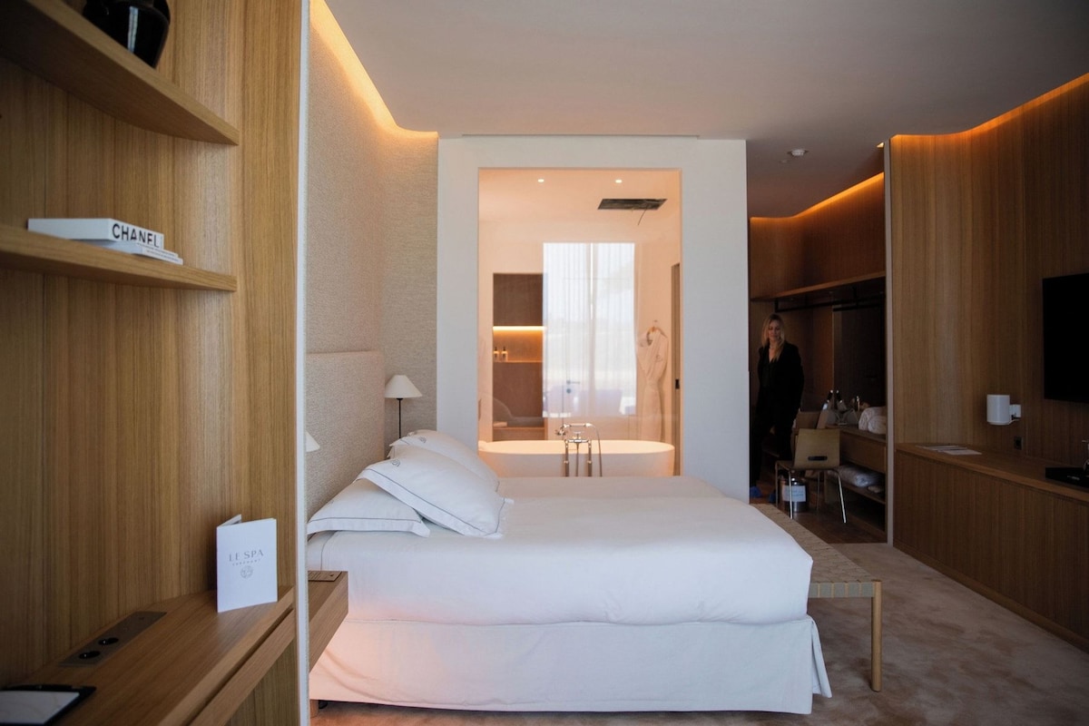 Ein Hotelzimmer mit Bett, Nachttischen, Fernseher und einem Badezimmer mit Badewanne sowie einem Spiegel.