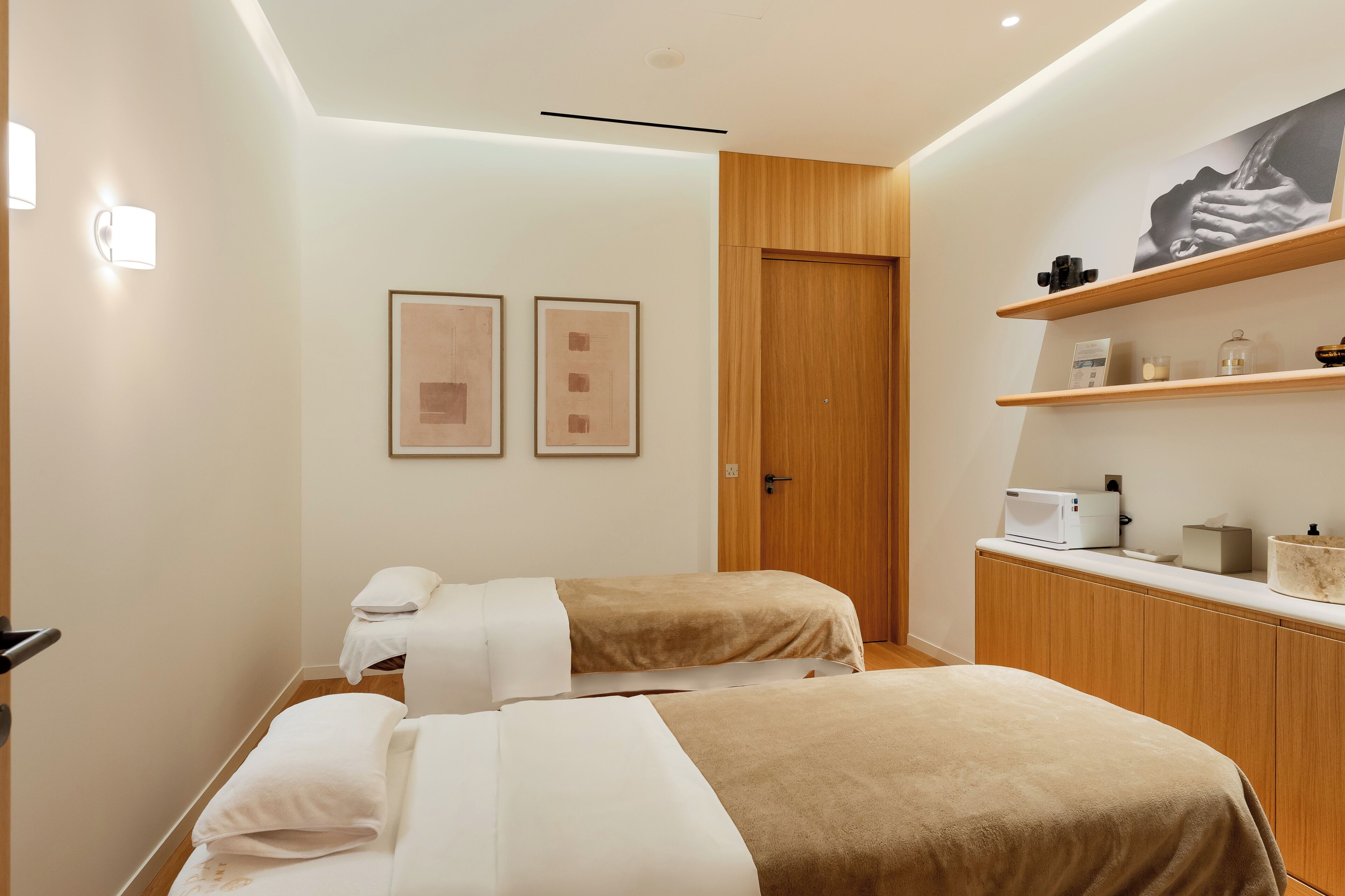 Une chambre d’hôtel moderne avec deux lits, une armoire en bois, un four à micro-ondes et une œuvre d’art encadrée au mur.
