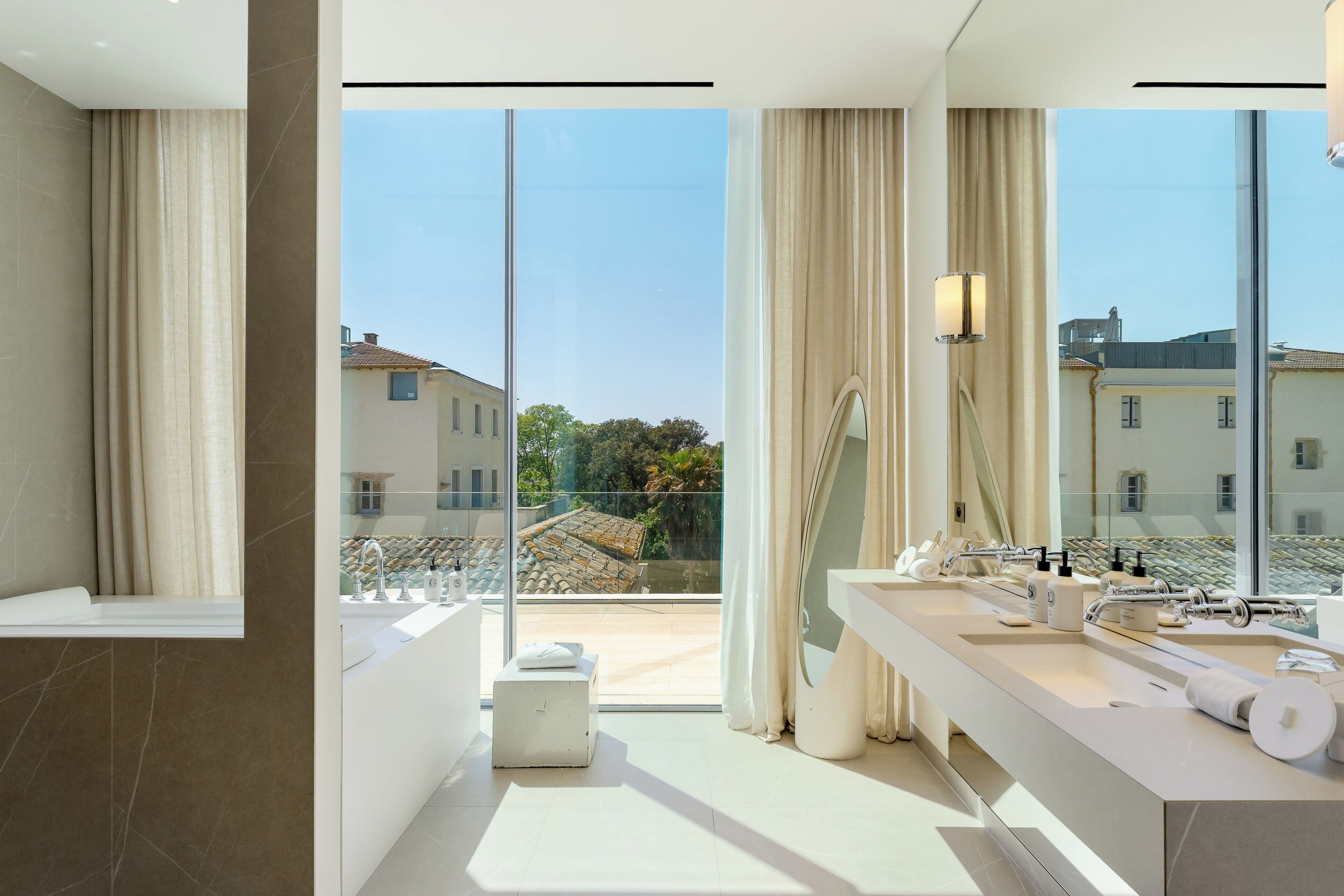 Un baño moderno con un ventanal amplio, una bañera, un lavamanos con espejo y una zona de ducha.