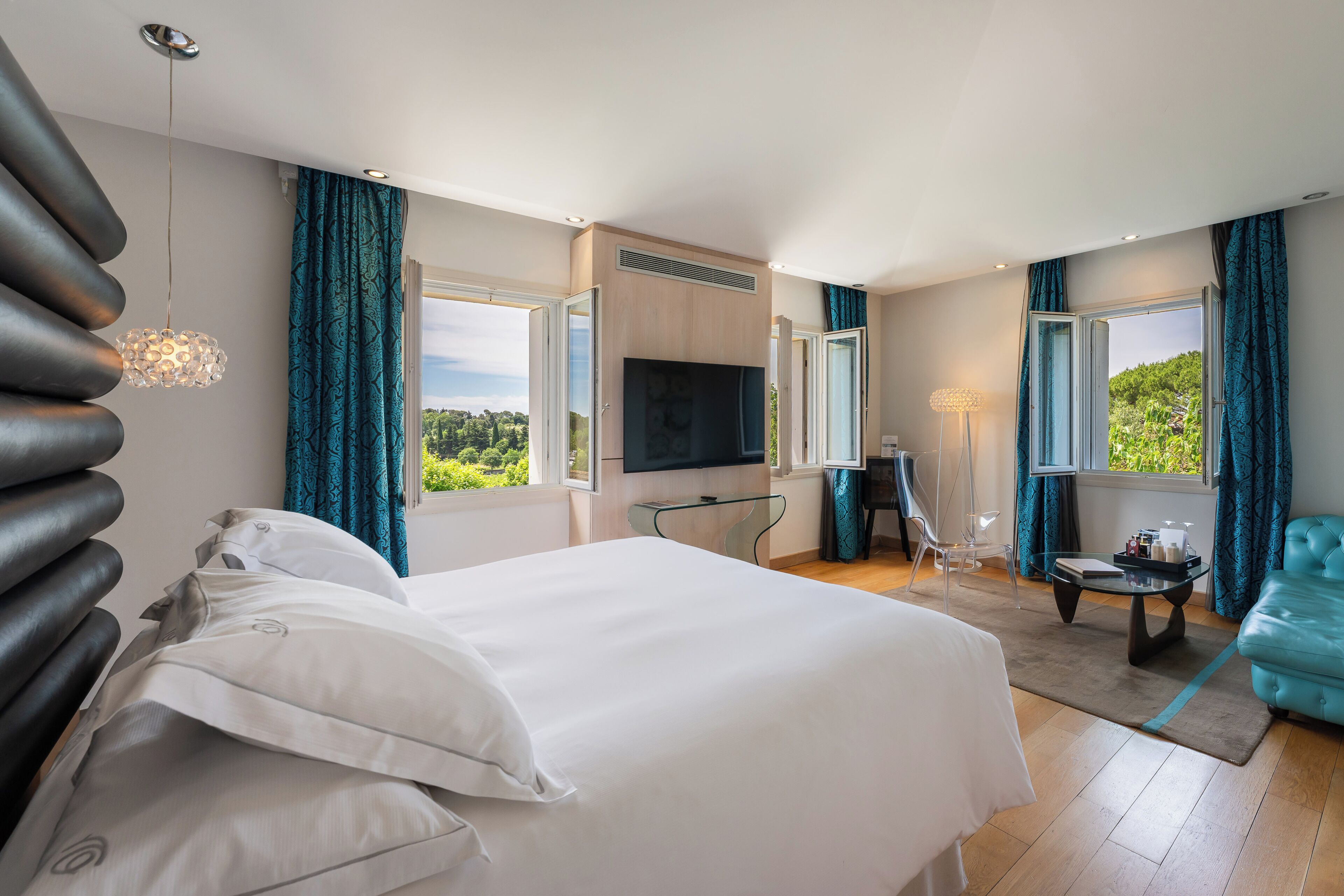 Habitación de hotel con cama, televisión, escritorio y vista a zonas verdes.