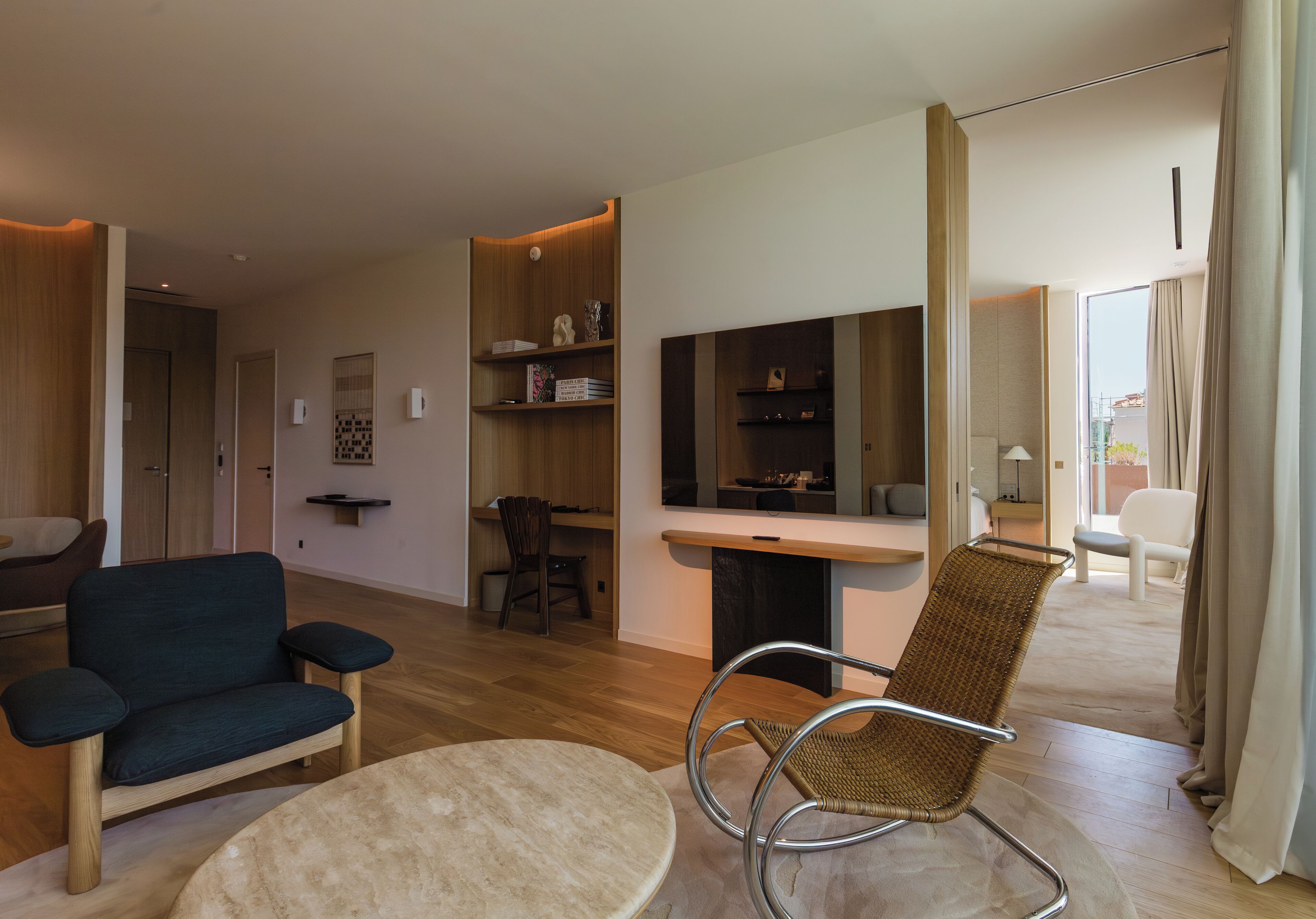 A modern living room with a sofa, a wicker chair, a round table, and a TV.