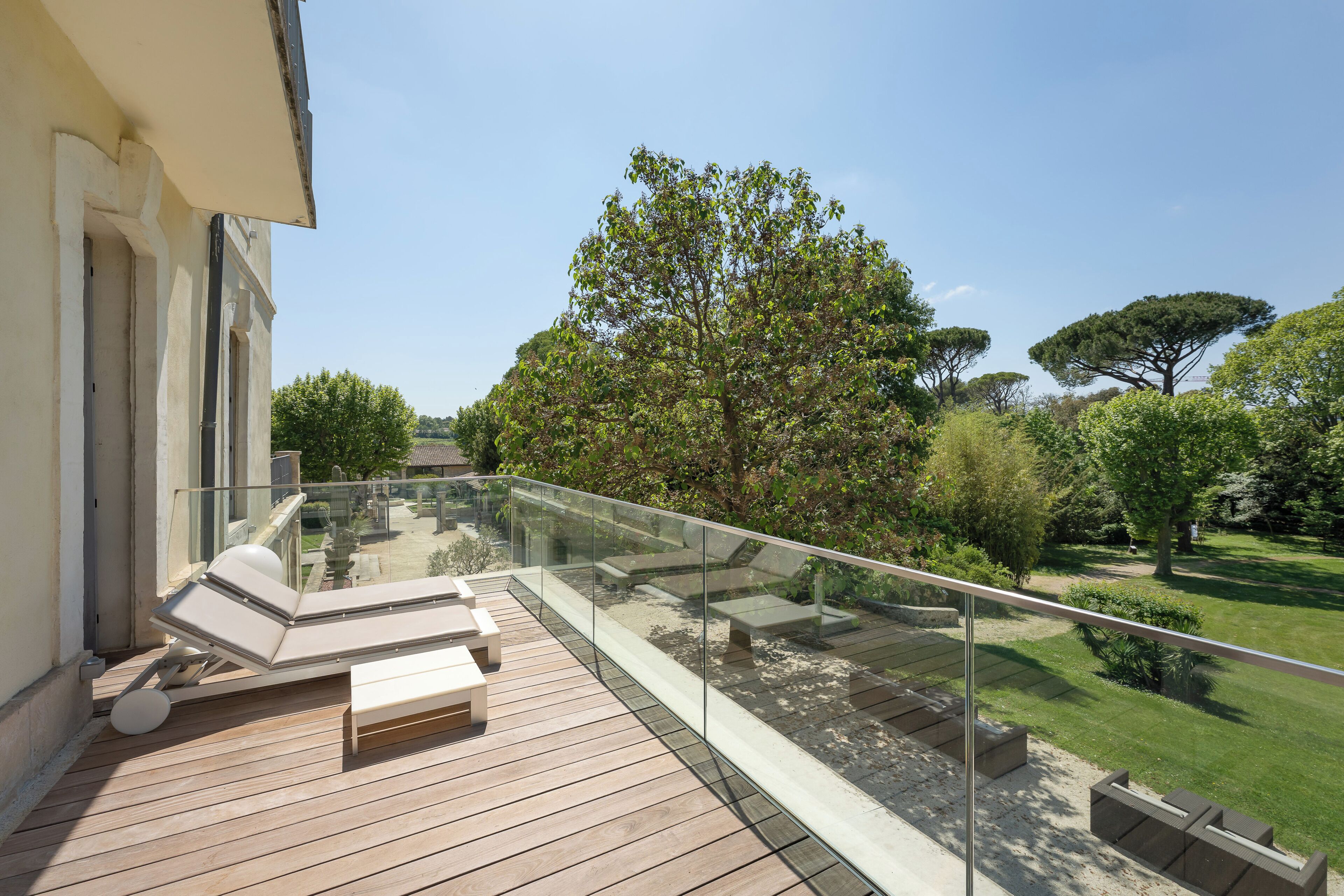 A balcony with a glass railing, wooden deck, and outdoor seating.