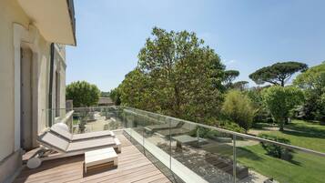 A balcony with a glass railing, wooden deck, and outdoor seating.