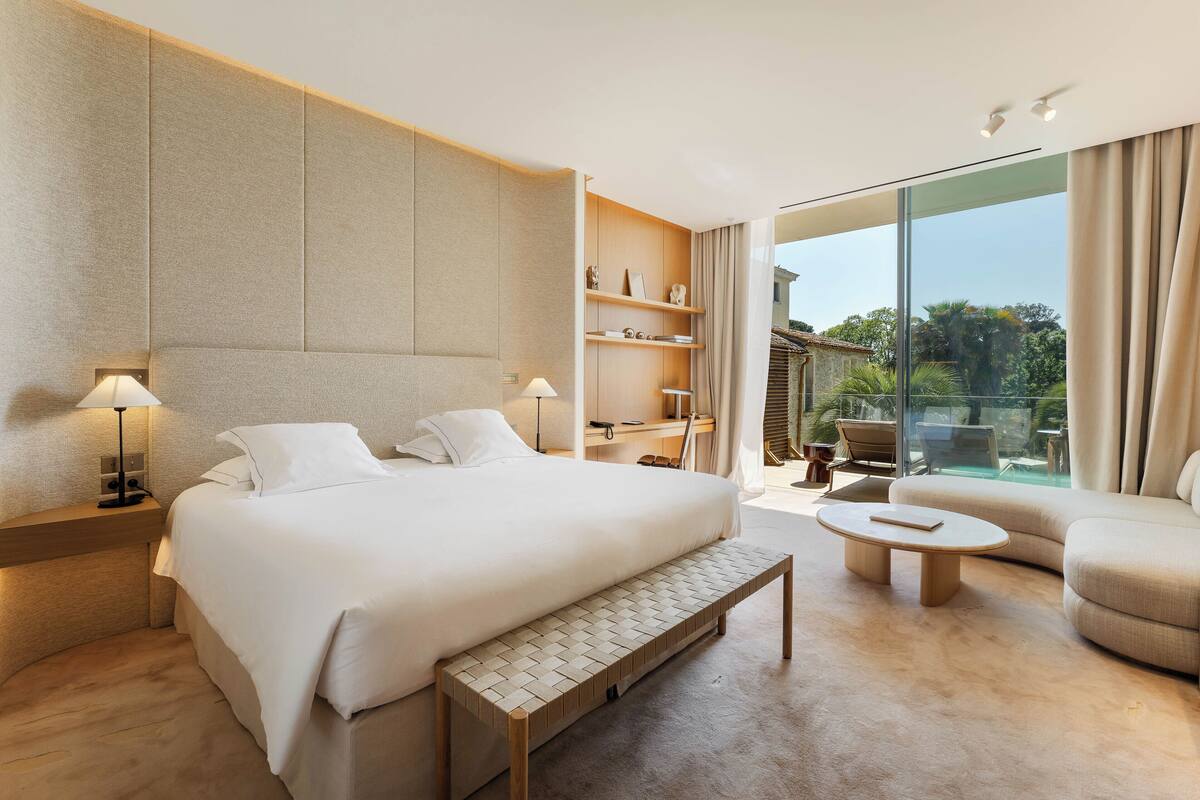 Een moderne hotelkamer met een groot bed, een kleine zithoek, een bijzettafeltje en een balkon met uitzicht.