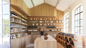 A wine cellar with wooden shelves and racks, a central table with a vase, and a wine rack against the wall.
